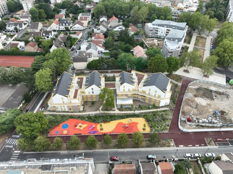 Suivi de chantier par drone — vue aérienne d'une résidence livrée avec cour paysagée et aire de jeux colorée en milieu urbain, Dronexperts